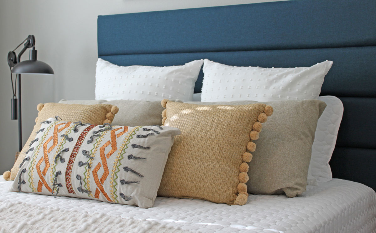 Closeup of bed with variety of colorful pillows